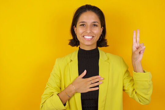Young hispanic businesswoman wearing casual turtleneck sweater and jacket smiling swearing with hand on chest and fingers up, making a loyalty promise oath. - Powered by Adobe