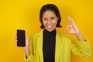 Young hispanic businesswoman wearing casual turtleneck sweater and jacket holding in hands cell...