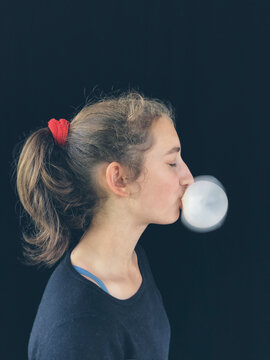 Teenage girl blowing large bubble gum bubble, just moments before it pops