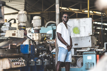 Fototapeta na wymiar Portrait photo young stylish black man in a white T-shirt and glasses in old factory. Street photo. african american people.