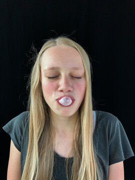Teenage girl blowing bubble gum bubble