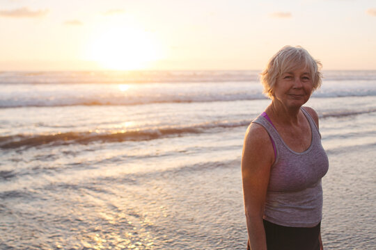 Vibrant mature woman enjoying herself on the beach at sunset