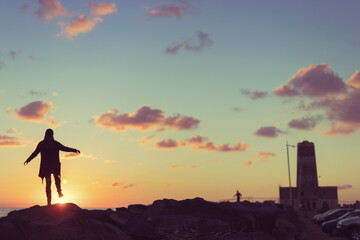Woman at sunset by the old lighthouse