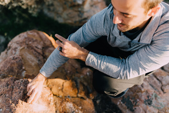 A man scratching a rock against a boulder
