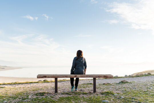 A woman sitting on a bench looking at a mountain view