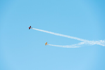 Planes dropping smoke and doing aerial acrobatics on a blue sky with space for text. 