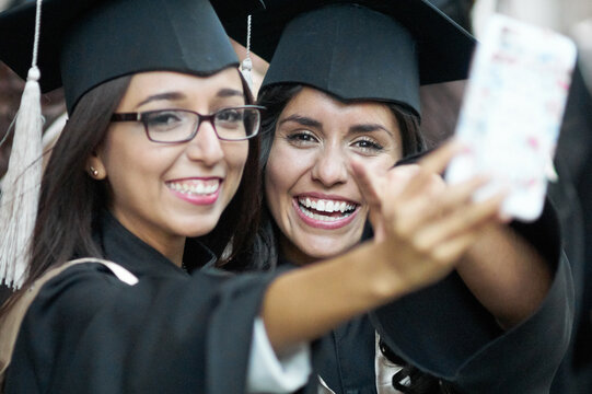 Two happy female students celebrating graduation with selfie
