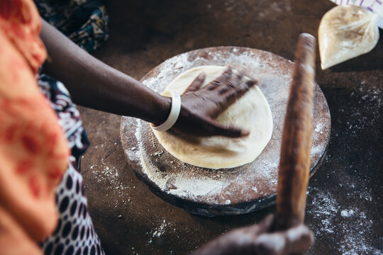 Rural African villager kneading dough and making bread and cooking in her kitchen