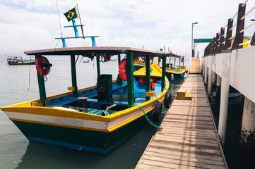 Fototapeta na wymiar Colorful boats next to a wooden dock at the Harbor of Porto Belo, Brazil.