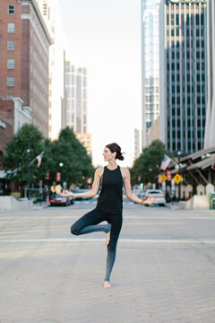 Beautiful woman standing in the middle of the street in a yoga position