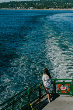 young woman standing at back of deck on a ferry