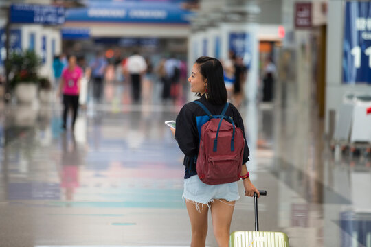 One young Asian woman in airport with suitcase