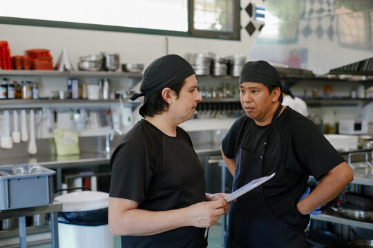 Chef and cook talking and organizing the purchase orders of the week