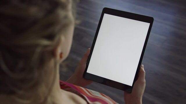 Woman holds tablet device in portrait orientation with blank white screen