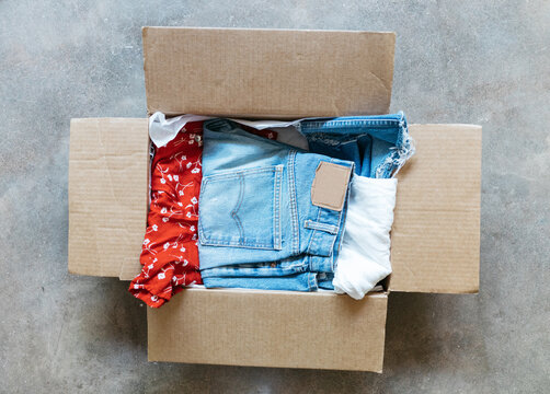 Vintage clothing packed in cardboard box on floor for subscription service mailing