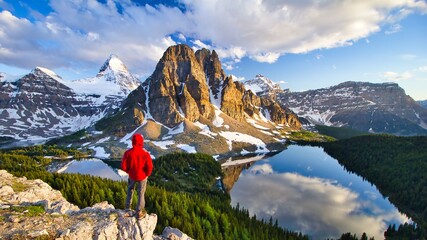 Hiker person overlooking Mount Assiniboine with Magog, Sunburst and Cerulean lakes as seen from Nub Peak, British Columbia, Canada