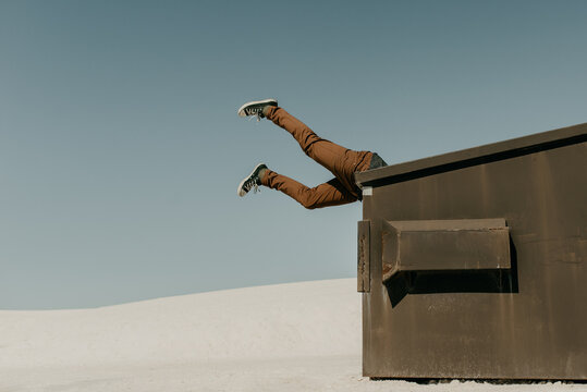 Garbage in, Garbage Out Idiom Concept of human legs flying in the air with his head stuck in the trash