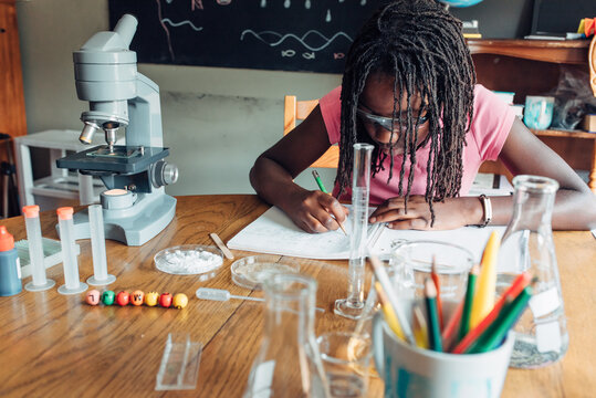 Homeschooled black girl taking notes about an experiment
