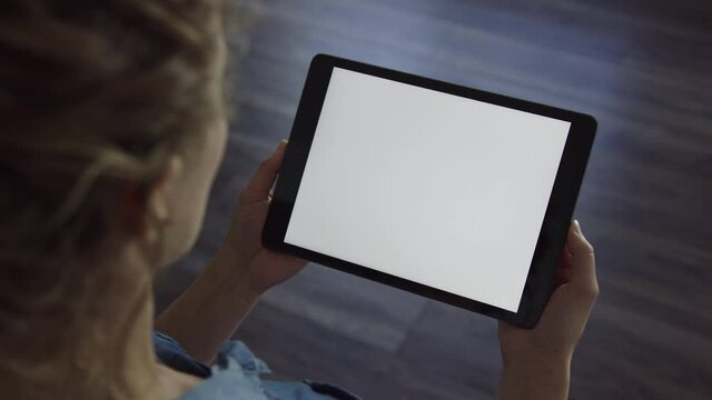 Woman holds tablet device in landscape orientation with blank white screen
