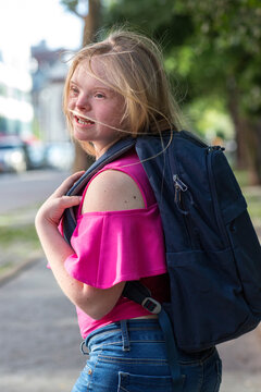 Girl with Down syndrome carrying a backpack.