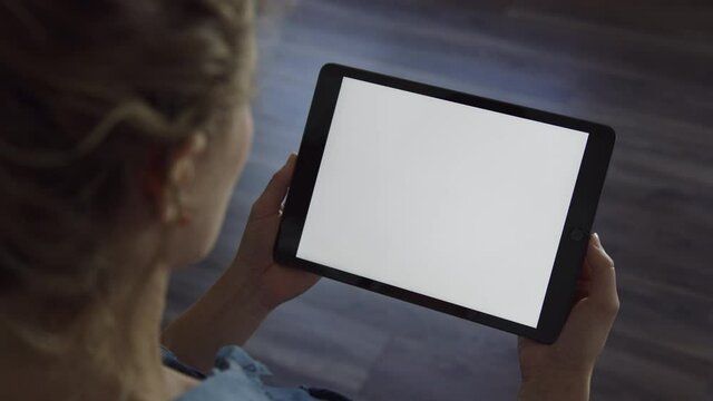 Woman holds tablet device in landscape orientation with blank white screen