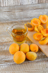 Tea with apricots in a glass mug on wooden and cutting board background, close-up.