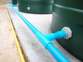PVC pipe connecting water tank. The blue plastic pipe connects all the green water tanks together, a water reserve concept. Selective focus