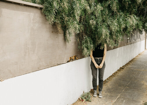 Mysterious woman hiding behind willow tree leaves
