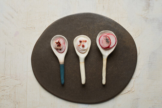 Trio of ceramic spoons with thin sliced vegetables and toppings