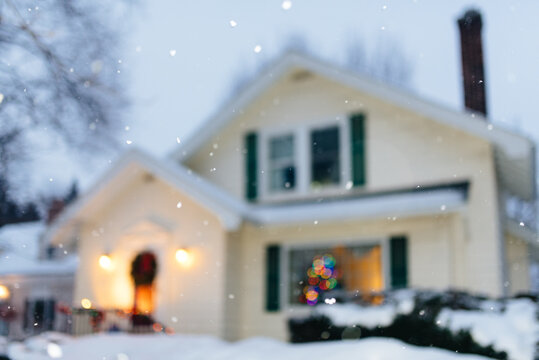 Snow falling outside of a suburban home at christmas