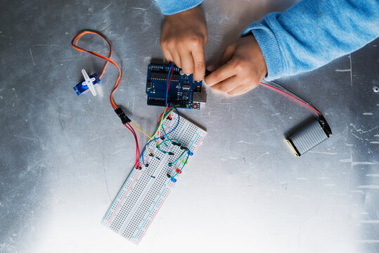 Boy connecting electronical parts to create his first little robot