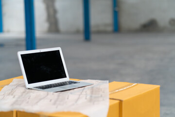 Laptop computer and blueprint plan for building warehouse.