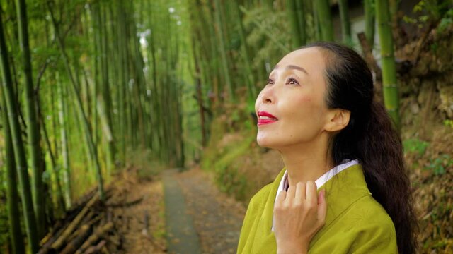Elegant Japanese woman walking through a bamboo forest in Kyoto Japan