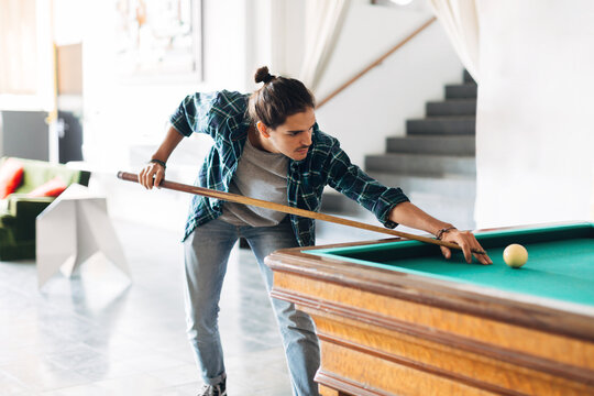 Portrait of creative young man playing billiard in a co-working office.
