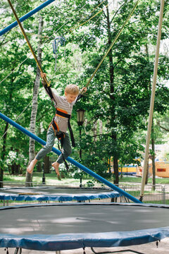Side view of blond boy jumping on trampoline bungy