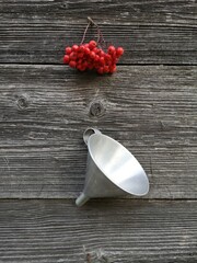 bunch rowan berries and metal funnel hanging on old wooden wall