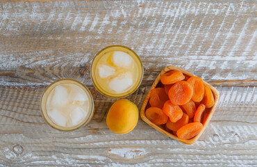 Dried apricots in a wooden plate with juice, fresh apricot flat lay on a wooden background