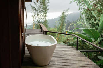 Outdoor white stone empty bath over green tropical nature background. Spa relaxation concept in...