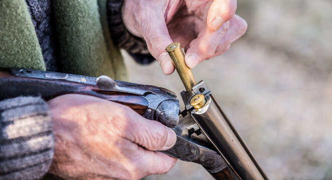 Old man putting ammunition in a hunting rifle-(loading shotgun)