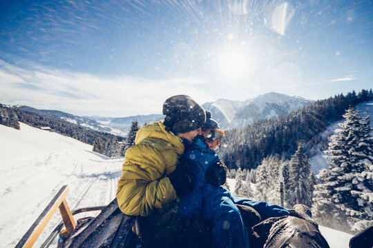 mother and son on the back of a snowmobile enjoying snowcovered landscape
