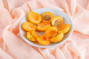 Apricots in a plate on a pink textile background. high angle view.