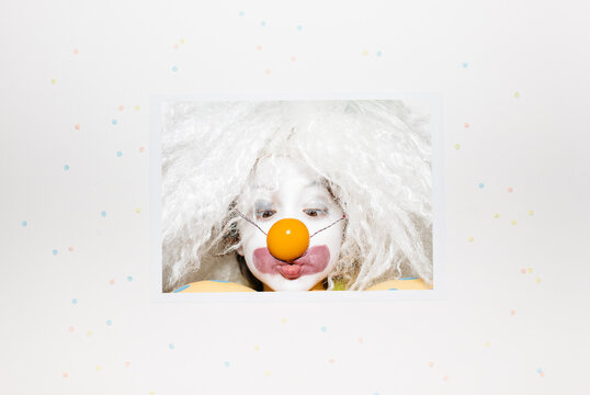 Printed headshot photo of a clown with an egg yolk on his nose that he is watching with crossed eyes