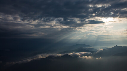 beautiful landscape of hills silhouette during sunrise. light breaking through cloud cover.