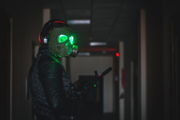 Futuristic soldier in gas mask with a rifle in a dark hall.
