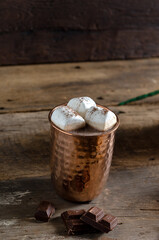 The dessert food vintage style : The Marshmallow with hot chocolate in copper cup on the wooden table. Background copy space for copy text