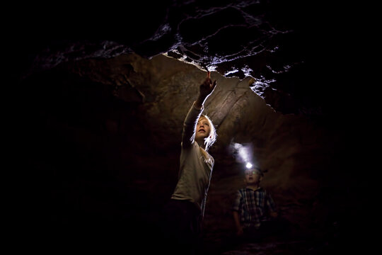 Girl and Boy Exploring A Dark Limestone Cave Underground