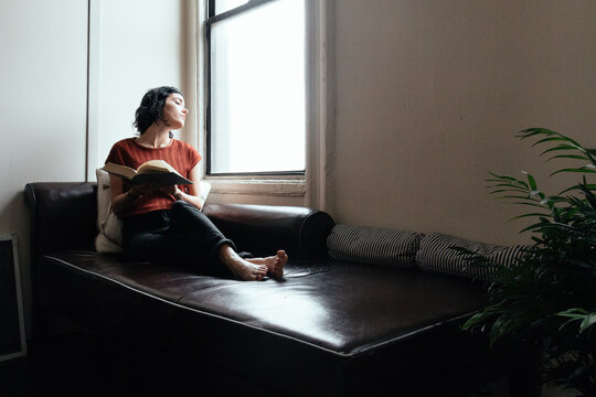 Woman reading a book on a sofa