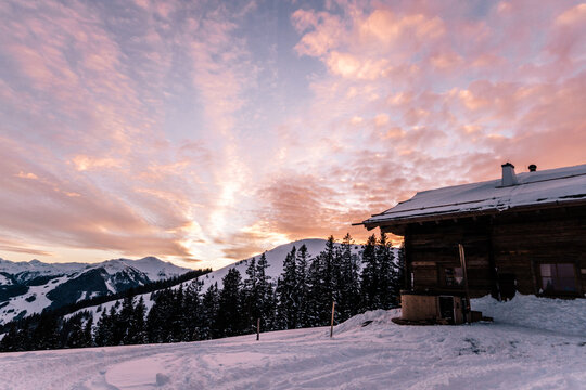 wooden alpine cabin with jacuzzi in snowcovered mountain landscape at sunset