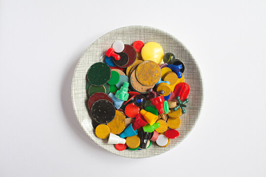 A small plate / bowl filled with colourful vintage game pieces