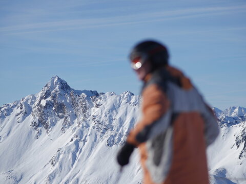 person in ski clothing in front of snowy moutain range